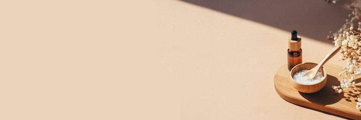 Amber dropper bottle with serum, tonic or essential oil and bowls filled with white bath sea salt...