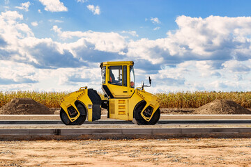 Vibratory road roller lays asphalt on a new road under construction. Close-up of the work of road...