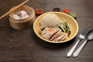 steamed Hainanese chicken rice crystal har gow transparent prawn shrimp meat stuffed dim sum in bamboo steamer green red chilli ginger soya sauce cucumber carrot on retro enamel diner plate fork spoon