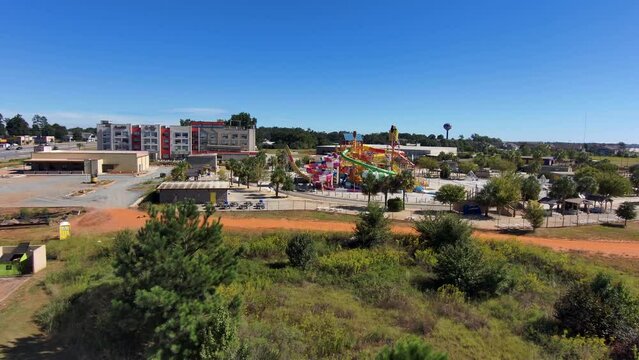 aerial footage of the city of Warner Robins Georgia with restaurants, offices buildings,  warehouses and a water park surrounded by vast miles of lush green trees with a gorgeous clear blue sky