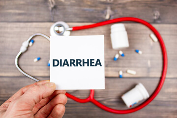 Diagnosis concept - diarrhea. A man holds a leaf in his hand with the word diarrhea on the background of pills. Dairy treatment.