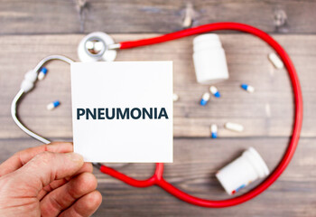 Diagnosis concept - pneumonia. A man holds a leaf in his hand with the word pneumomentia on the...