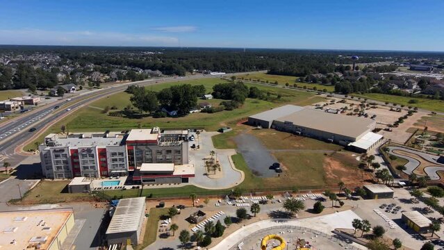 aerial footage of the city of Warner Robins Georgia with restaurants, offices buildings,  warehouses and a water park surrounded by vast miles of lush green trees with a gorgeous clear blue sky