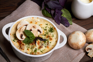 Chicken julienne with cheese, mushrooms and herbs in white plate on wooden board