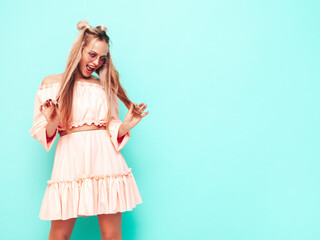 Young beautiful smiling female in trendy summer dress. carefree woman posing near blue wall in studio. Positive brunette model having fun.Cheerful and happy. Isolated