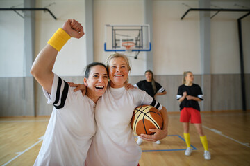 Group of young and old women, sports team players, in gym celebrating victory.