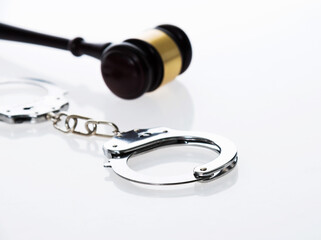 Wooden judge gavel and police handcuffs isolated on white background
