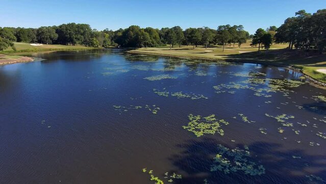 aerial footage of a gorgeous autumn landscape at Houston Lake with rippling blue water surrounded by lush green trees, grass and plants with a golf course and homes along the banks in Warner Robins