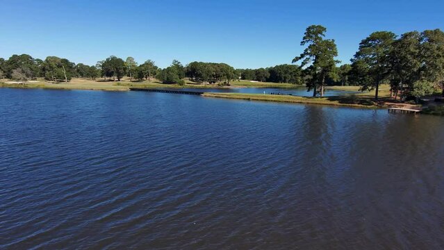 aerial footage of a gorgeous autumn landscape at Houston Lake with rippling blue water surrounded by lush green trees, grass and plants with a golf course and homes along the banks in Warner Robins