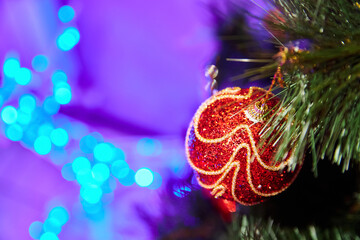 Close-up of a red Christmas ball on a Christmas tree against the background of blue lights