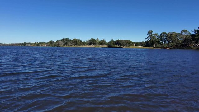 aerial footage of a gorgeous autumn landscape at Houston Lake with rippling blue water surrounded by lush green trees, grass and plants with a golf course and homes along the banks in Warner Robins