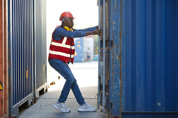 African factory worker or foreman opening the container door in warehouse storage