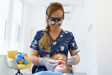 Young woman dentist doing doing preventive examination little girl. © Halfpoint