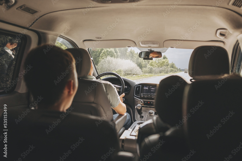 Wall mural young man holding steering wheel while driving car. road trip. local travel concept. thirst for adve