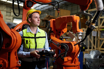 factory worker or engineer operating remote switch controller to control robot machine in the...