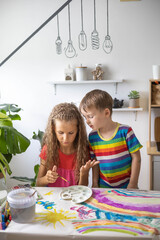 Confident cute boy and girl art drawing multicolored rainbow arch use paints and brush on table