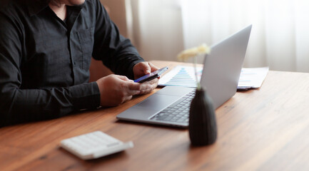 business woman working on a wooden table Using laptops and computers to assess and analyze the economy for successful investment in your company's business, business idea.