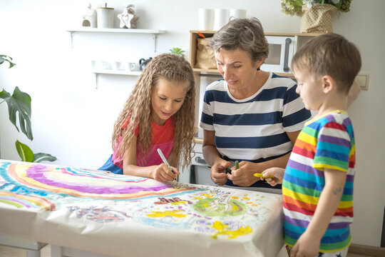 Family mother and kids drawing art picture on paper with multicolored chalks enjoy weekend