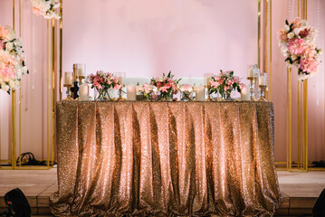 Festive table newlyweds covered with a tablecloth and decorated with composition of flowers and greenery in the wedding banquet hall. Wedding party. Wedding decor.