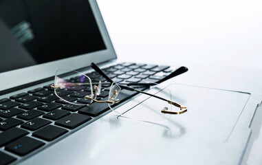 Close up of eyeglasses on laptop keyboard against white background