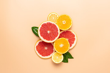 Composition of neatly arranged ripe grapefruit, orange, lemon, green leaves on beige background....