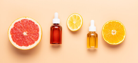 Cosmetic serum, vitamin C extract. Slice of grapefruit, orange, lemon and set of cosmetic bottles on beige background, top view