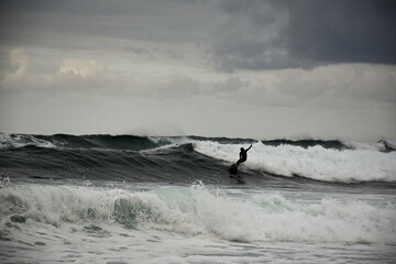 Fotografia di un surfista che fa surf nell'oceano in una giornata nuvolosa