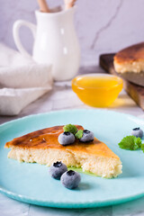 Appetizing thin cheesecake with honey and blueberries on a plate. Homemade pastries. Vertical view