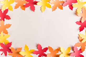 Frame made of cut out maple multi-colored leaves from craft paper. Autumn decoration.