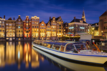 Damrak, Amsterdam, Netherlands. View of houses and boats during sunset. The famous Dutch canals and...