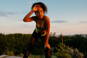 Young black woman resting after run at summer park