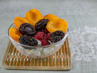 A bowl of cottage cheese and apricots, raspberries and prunes on top. Close-up. 