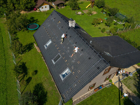 High angle view of men worker installing solar photovoltaic panels on roof, alternative energy, saving resources and sustainable lifestyle concept.