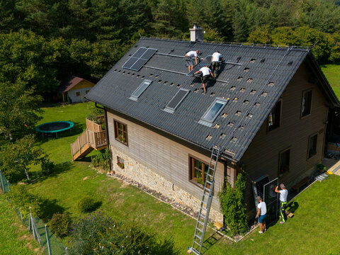 High angle view of men worker installing solar photovoltaic panels on roof, alternative energy, saving resources and sustainable lifestyle concept.