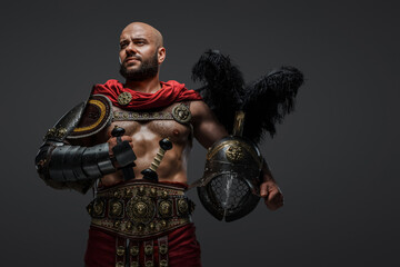 Shot of muscular bald gladiator with beard with two swords and plumed helmet.