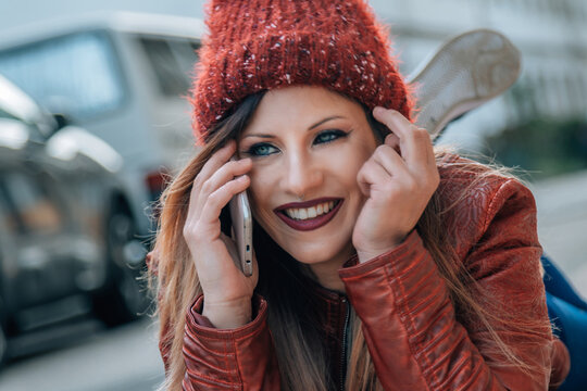 young smiling hipster woman lying with phone on the street