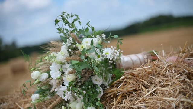 A white wedding bouquet on a hay bale sways in the wind