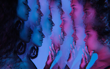 Horizontal multiple exposure studio shot of modern young ethnically diverse women standing in front of each other in blue and pink neon light 