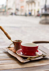 Traditional Turkish coffee is served in a cup and a metal coffee pot on the terrace of street cafe.