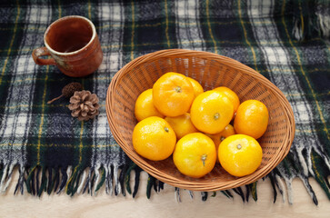 カゴに入ったみかんと松ぼっくりとコーヒーカップ（上から）