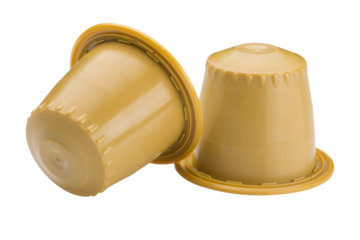 Two yellow capsules with ground coffee, for a capsule coffee machine, on a white background, one capsule is overturned, isolate