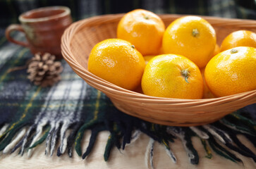 カゴに入ったみかんと松ぼっくりとコーヒーカップ（横から）