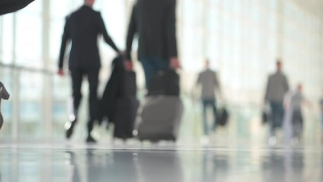 Woman in business outfit walking in slow motion, man with suitcases in the background