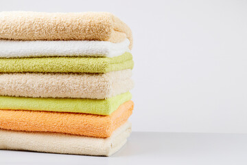 A stack of clean towels on a light gray background. Cotton towels on table. Space for text