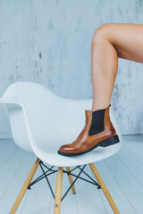 Close up of female legs in brown leather Chelsea boots. New autumn collection of women's leather shoes 2022
