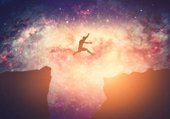 Making a dream come true. Man jumping between mountains on galaxy night sky