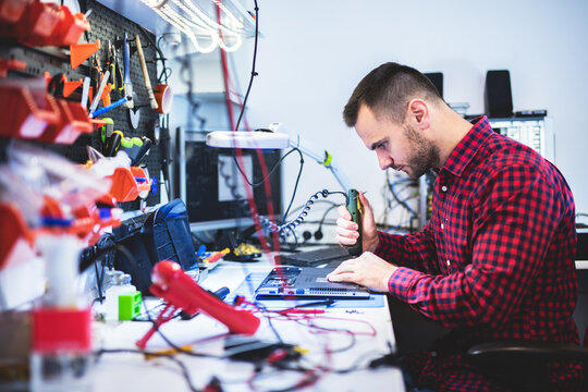 IT engineer technician repairing computer in electronics service shop - Powered by Adobe