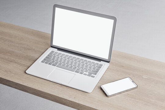 Close up of empty white laptop and smartphone on wooden desktop, mock up place on screen, concrete flooring background. 3D Rendering.