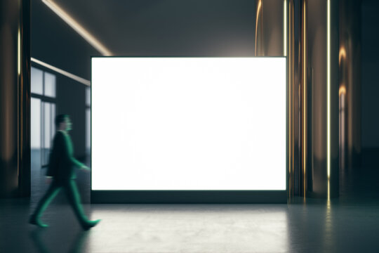 Walking Businessman By Blank White Illuminated Big Screen With Place For Your Logo Or Text Between Golden Pillars With Glossy Floor On Dark Empty Room Background, Mock Up