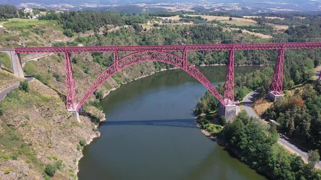 Scenic drone view of parabolic arched framework of railway bridge Viaduc de Garabit across river Truyere near Ruynes-en-Margeride in Auvergne, France